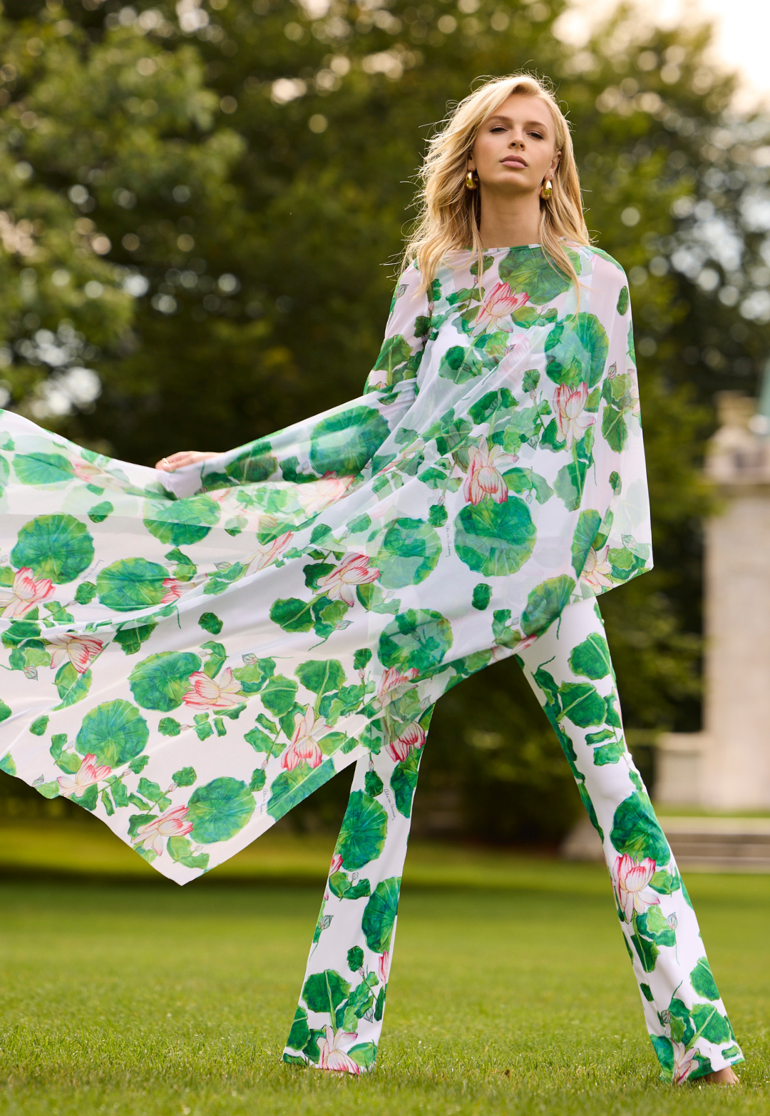 Woman wearing a green mesh kaftan with matching tank top and pants standing outdoors with trees in the background