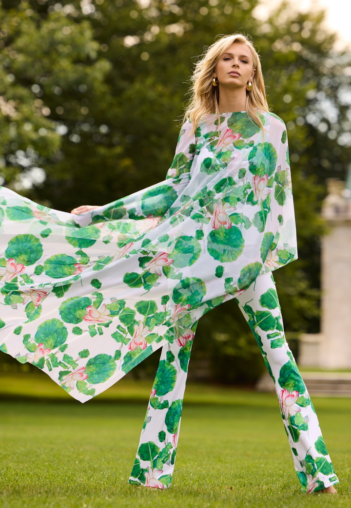 Woman wearing a green mesh kaftan with matching tank top and pants standing outdoors with trees in the background