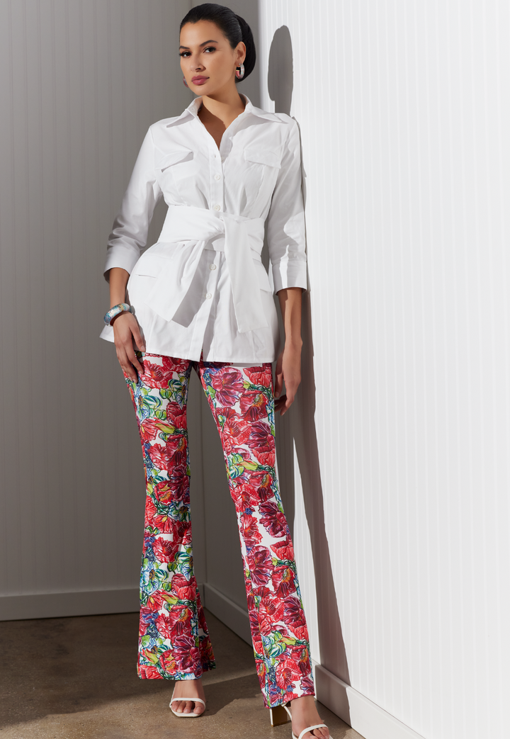 Woman wearing white cotton pique jacket blouse with stretch knit red floral printed pants by designer Ala von Auersperg for womens luxury travel clothing