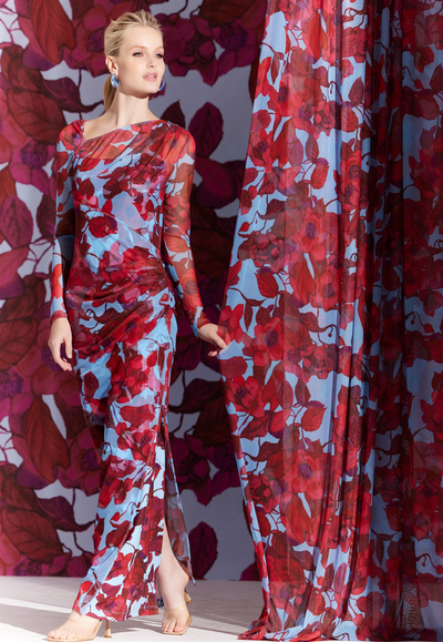 Woman wearing sheer mesh dress topper over a matching long stretch knit dress in a red floral print with a blue background by designer Ala von Auersperg for womens luxury travel clothing