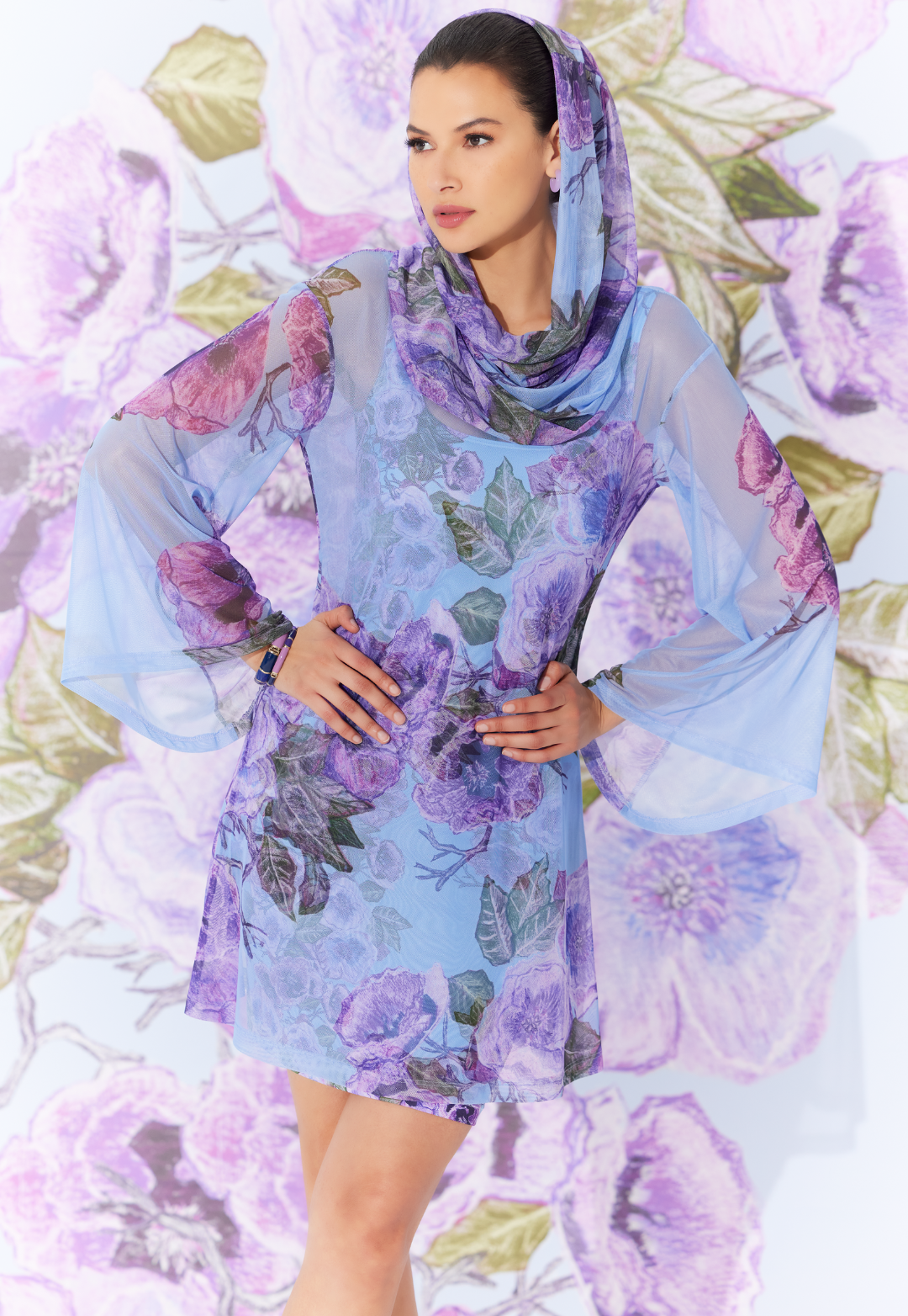 Woman wearing sheer hoodie over mini stretch knit dress in a matching purple floral print by designer Ala von Auersperg for womens luxury travel clothing