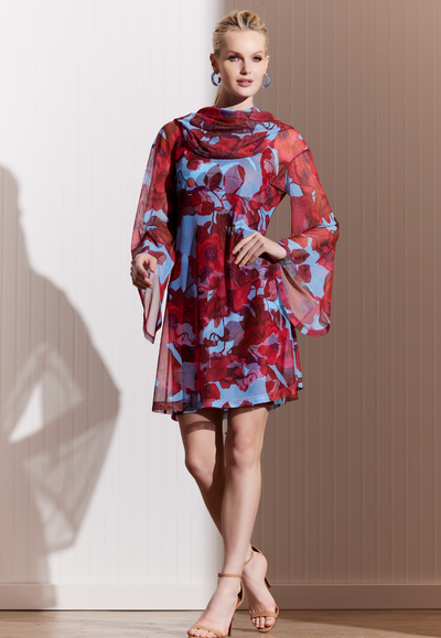 Woman wearing short mini sheer mesh hoodie dress over a matching mini stretch knit dress in a red floral print with a blue background by designer Ala von Auersperg for womens luxury travel clothing