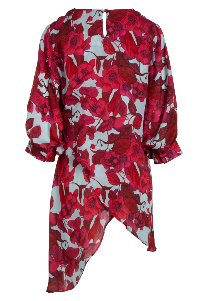 Flat image of a red floral printed silk blouse with a blue background by designer Ala von Auersperg for womens luxury travel clothing