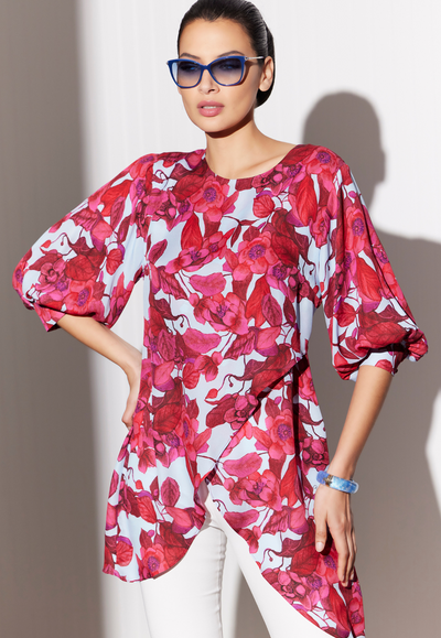 Woman wearing asymmetrical silk blouse in a red floral print by designer Ala von Auersperg for womens luxury travel clothing