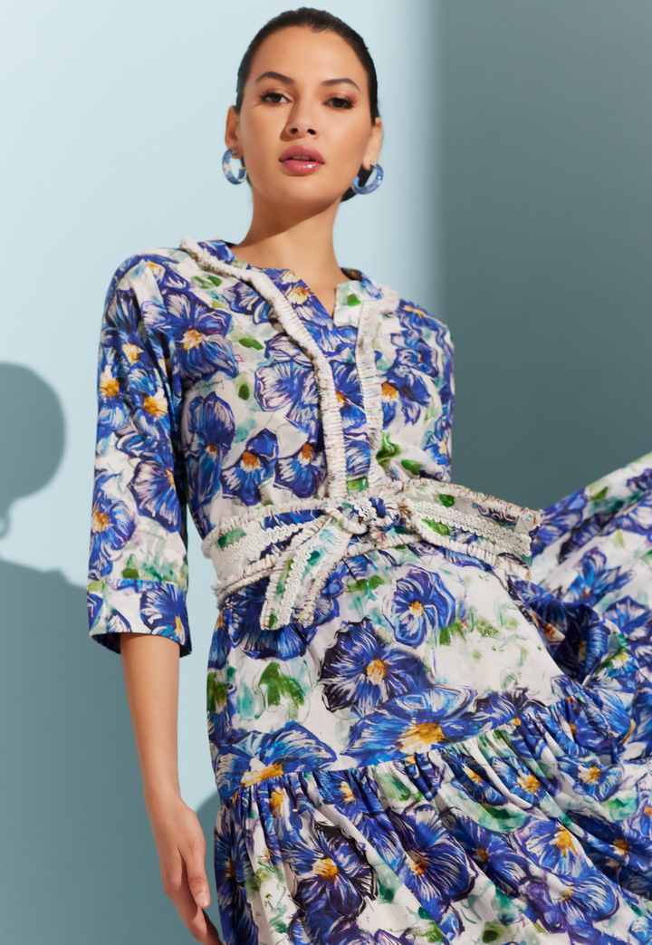 Woman wearing cotton tunic with fringe trim in a blue floral print with a matching belt and cotton maxi skirt by designer Ala von Auersperg for womens luxury travel clothing