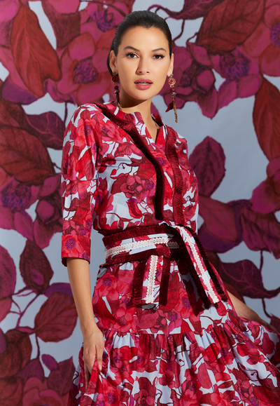 Woman wearing cotton tunic with fringe detail in a red floral print with a blue background by designer Ala von Auersperg for womens luxury travel clothing