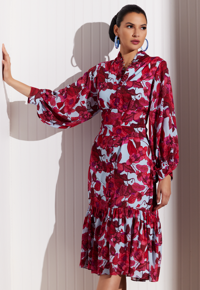 Woman wearing silk button up midi dress with bell sleeves in a red floral print by designer Ala von Auersperg for womens luxury travel clothing