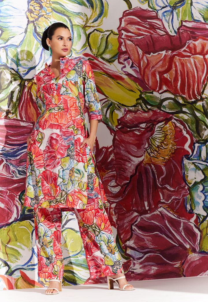 Woman wearing matching cotton tunic and pants in a red floral cotton print by designer Ala von Aursperg for womens luxury travel clothing