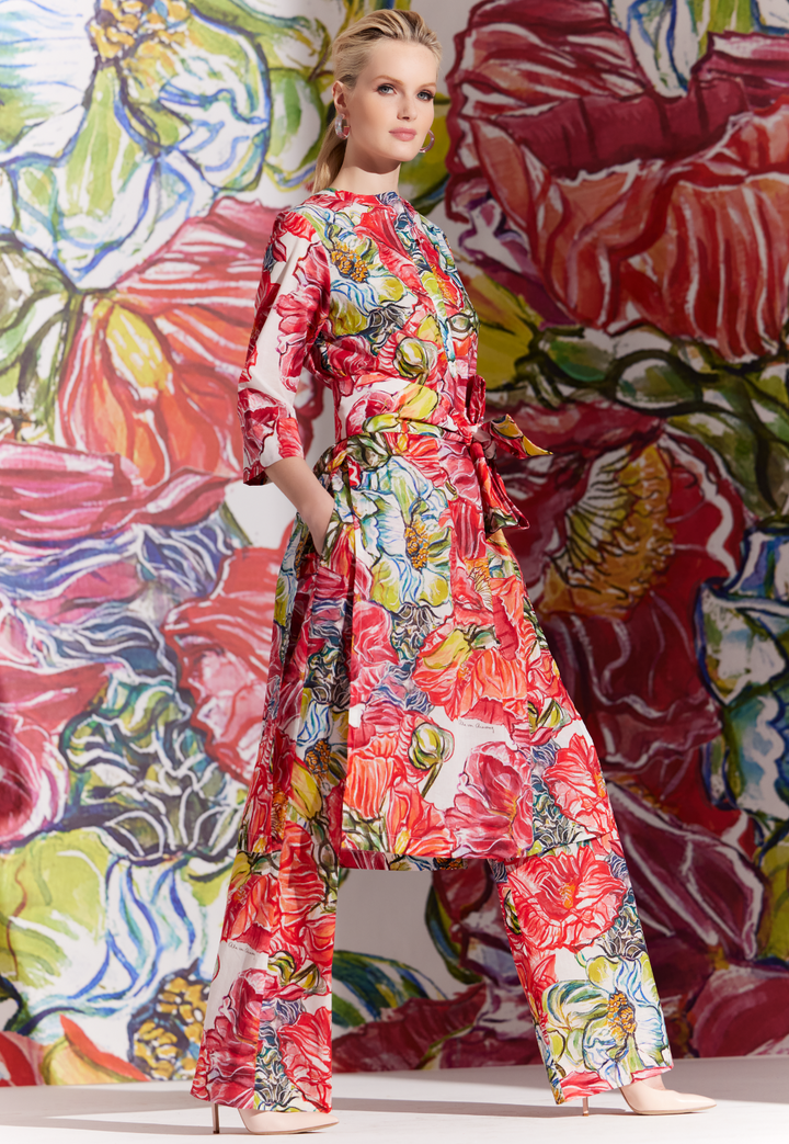 Woman wearing cotton pants with matching tunic and sash in a red floral print by designer Ala von Auersperg for womens luxury travel clothing