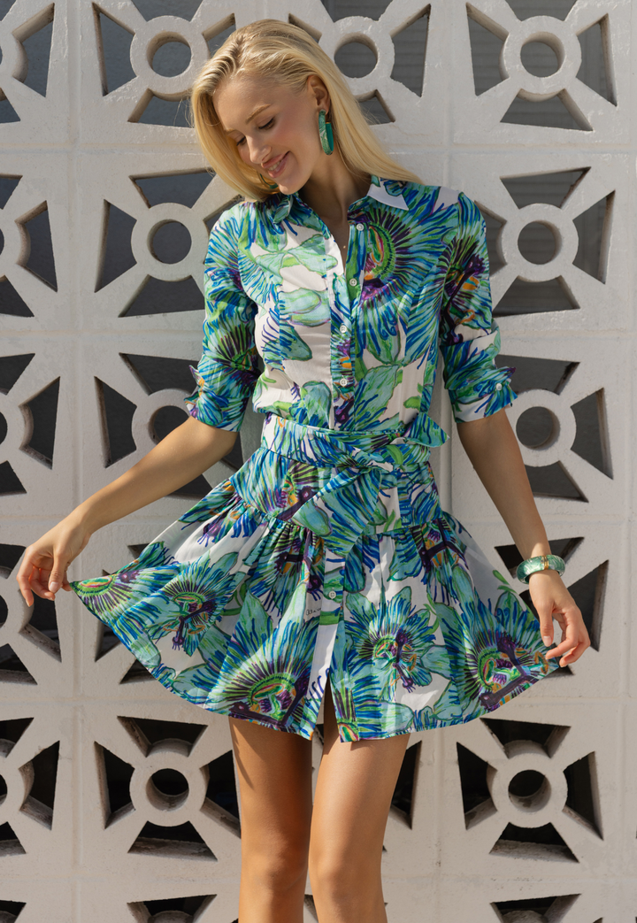 Woman wearing a green and blue floral print dress against a geometric patterned wall.