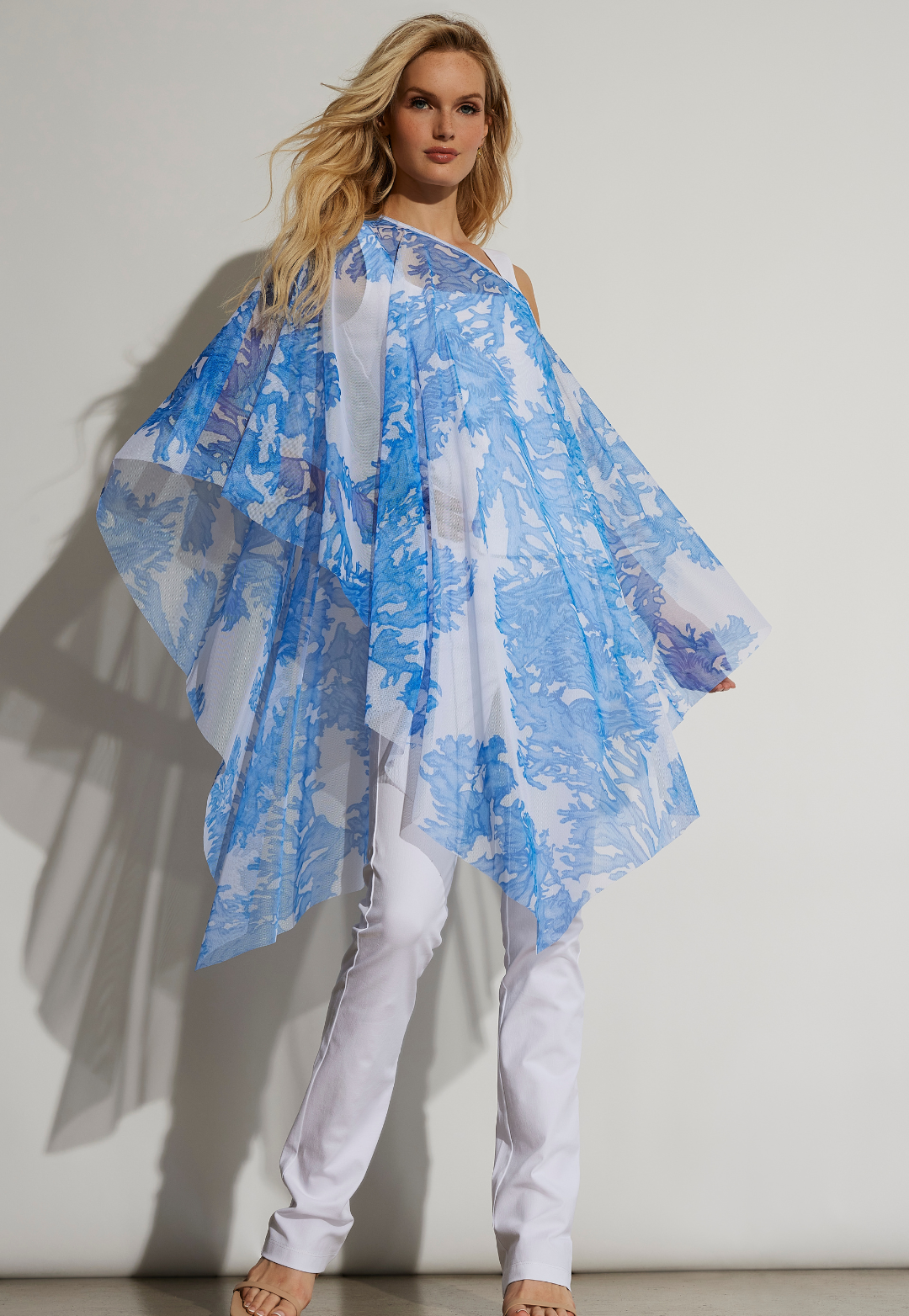 Woman wearing Artemisia Blue Coral sheer mesh poncho with white pants