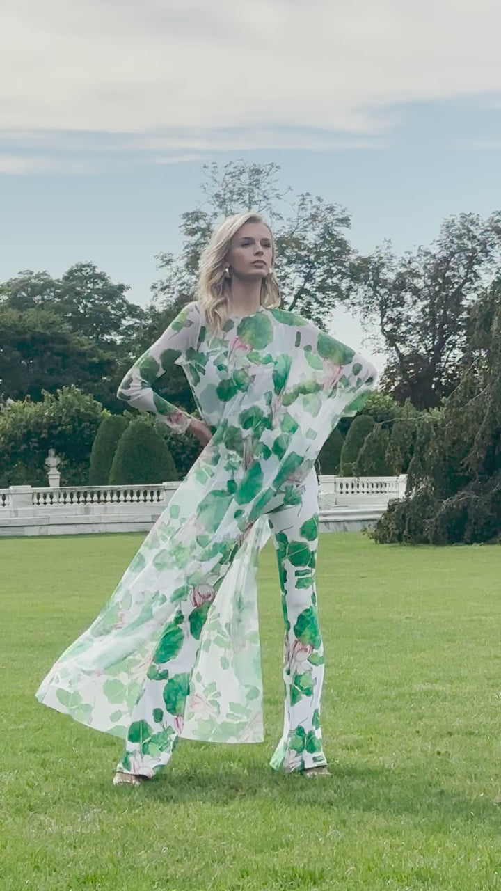 Video of a woman wearing a mesh poncho over a tank top and pants in a matching lillypad and floral print