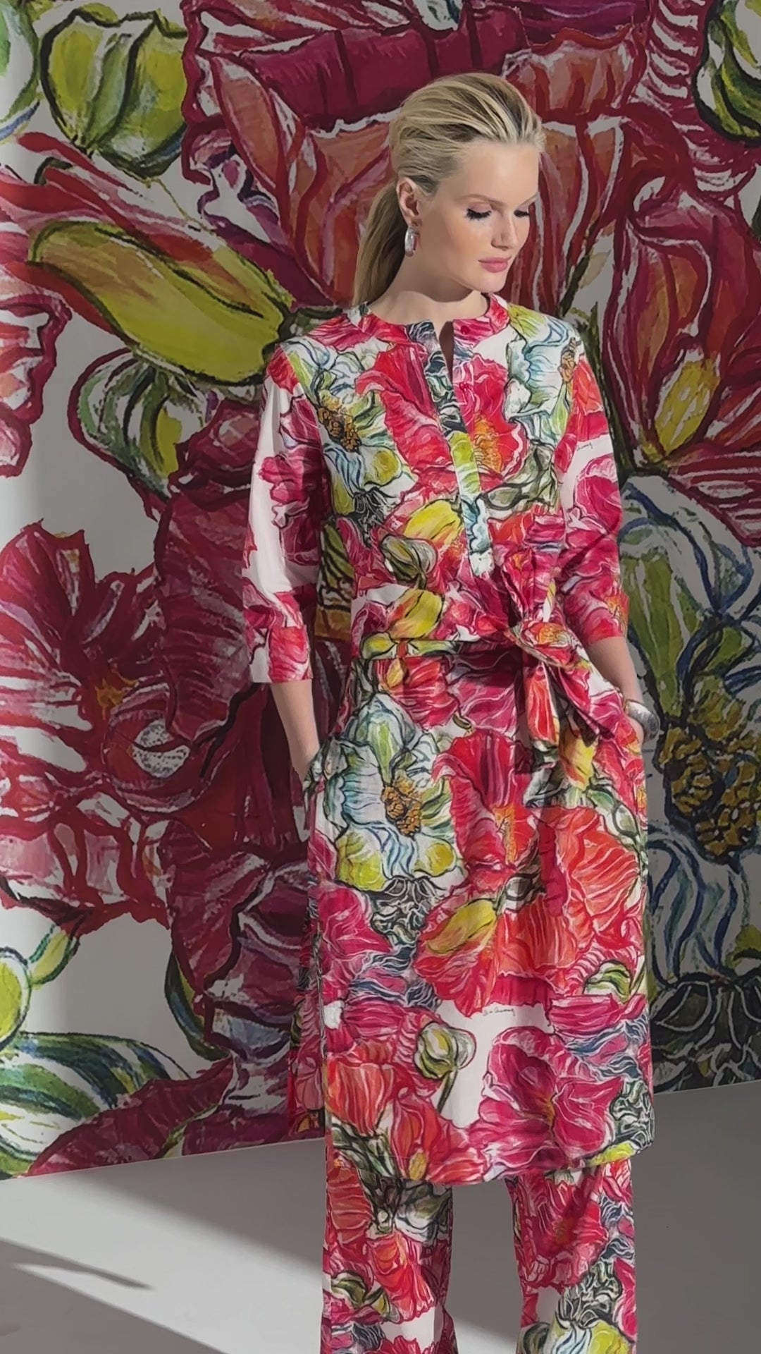 Woman wearing matching cotton tunic, sash, and pant, in a red floral print by designer Ala von Auersperg for womens luxury travel clothing