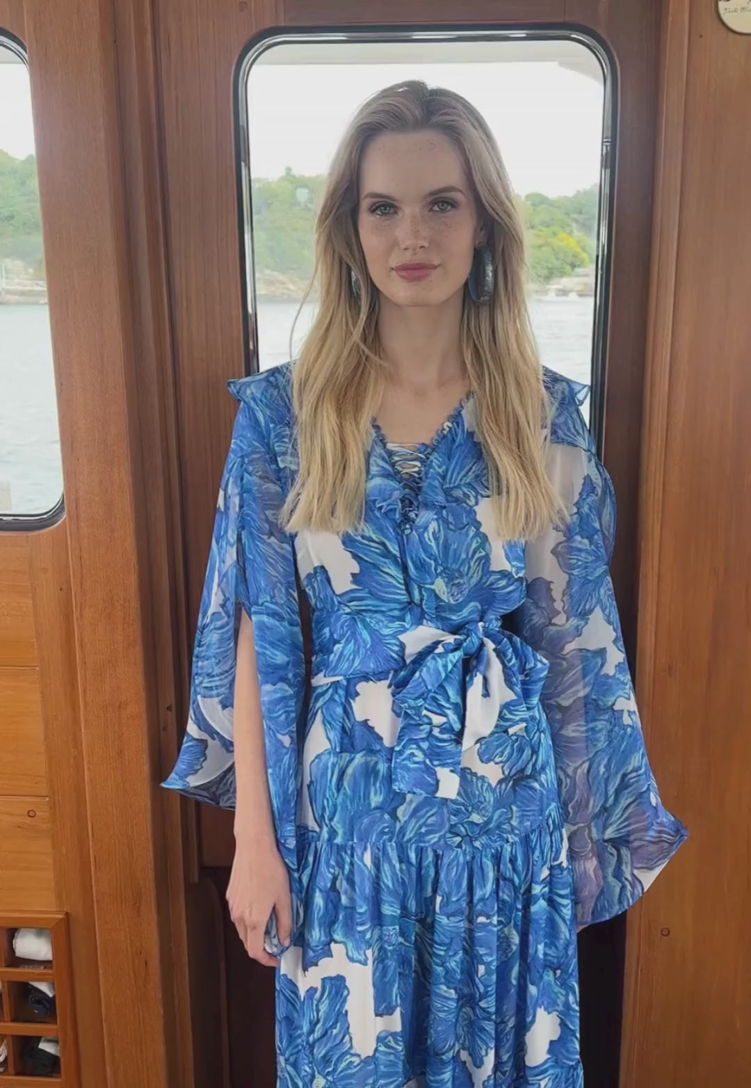 Video of a woman on a yacht wearing a blue floral printed silk formal designer dress by Ala von Auersperg for women's luxury travel clothing