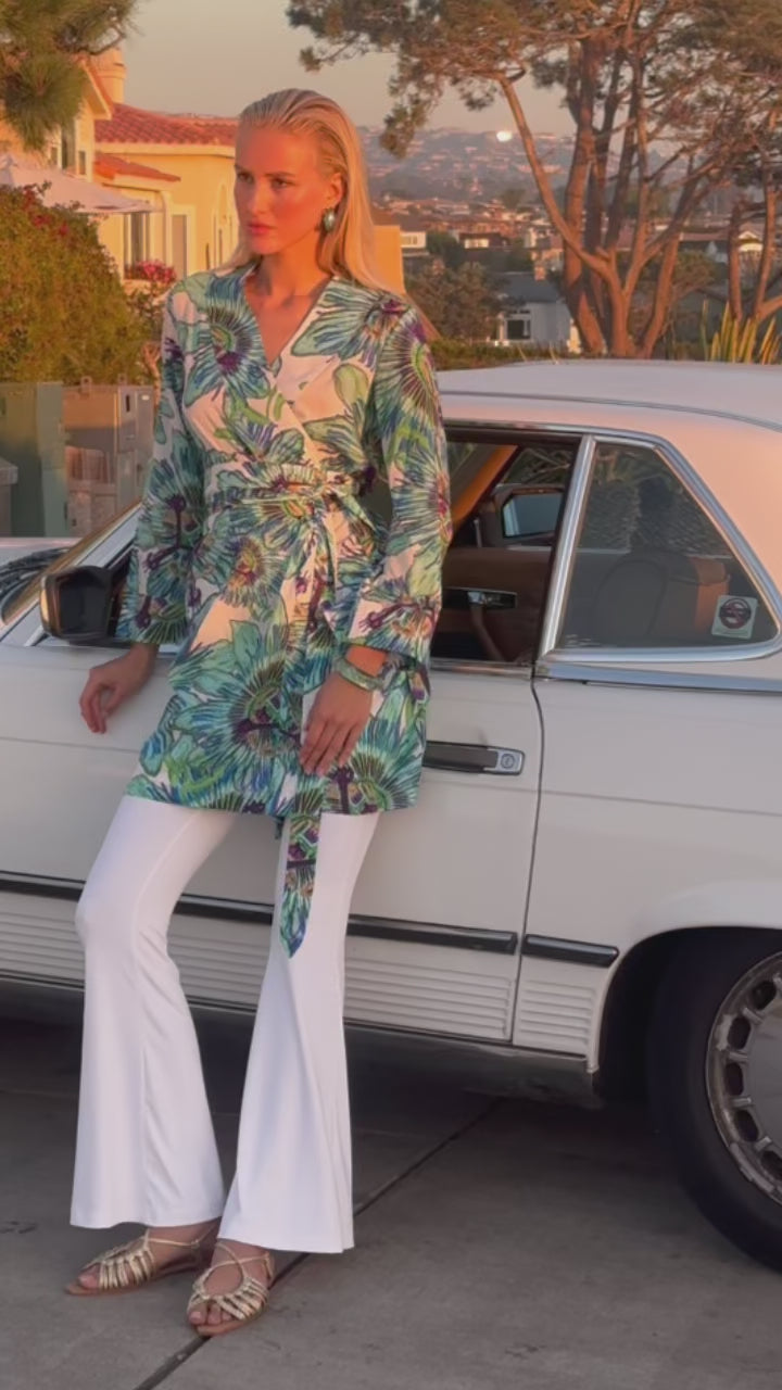 Video of a woman wearing a cotton floral kimono with white pants in front of a car