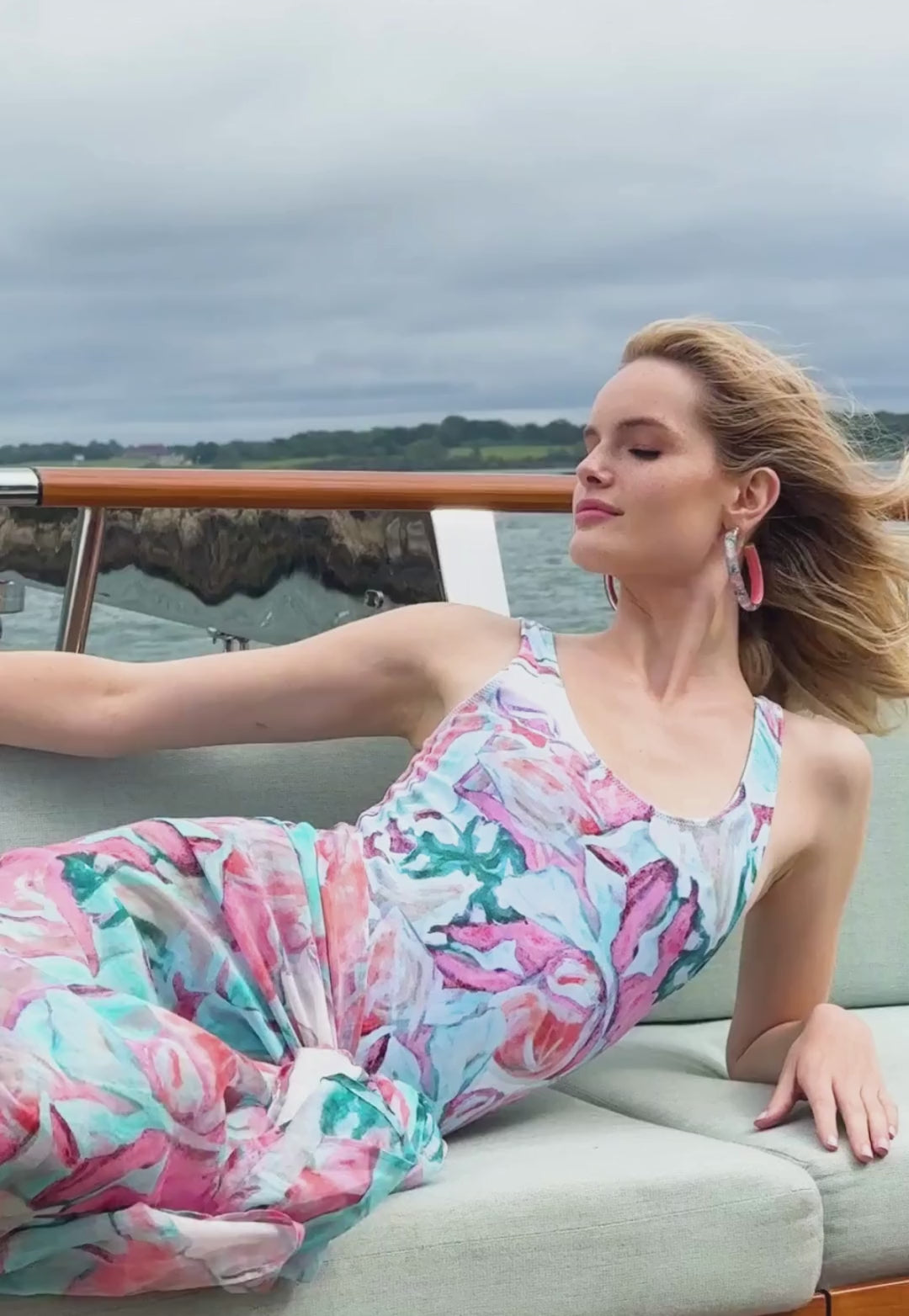Video of a woman wearing a bathing suit in a pink floral print with a matching cotton pareo on a yacht by designer Ala von Auersperg for women's luxury resort travel fashion