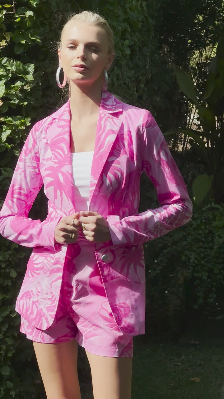 Video of a woman wearing a cotton blazer and shorts in a pink print in a garden