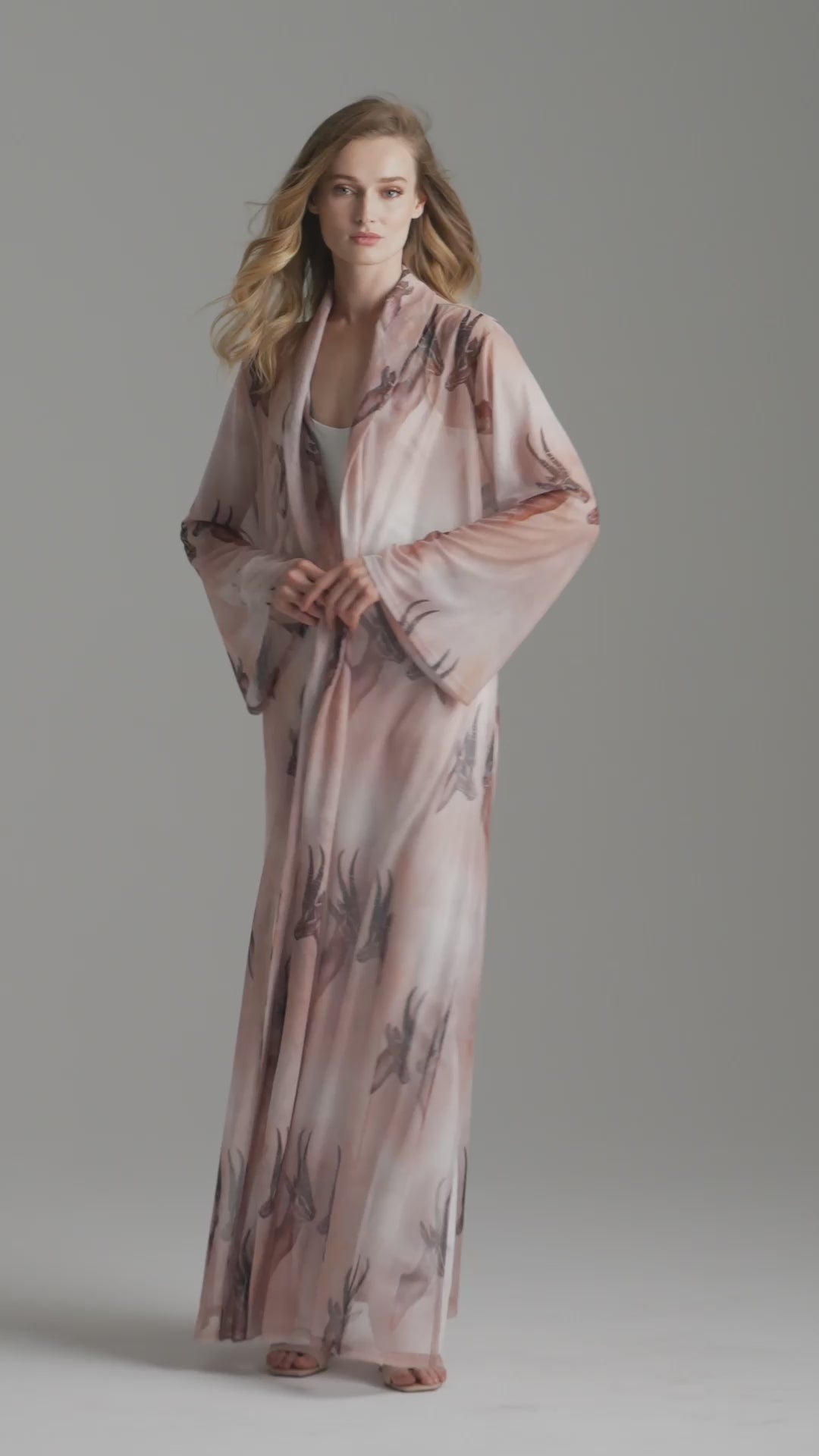 Woman wearing long mesh duster robe in brown deer print over white stretch knit tank top and pants by Ala von Auersperg for fall 2023