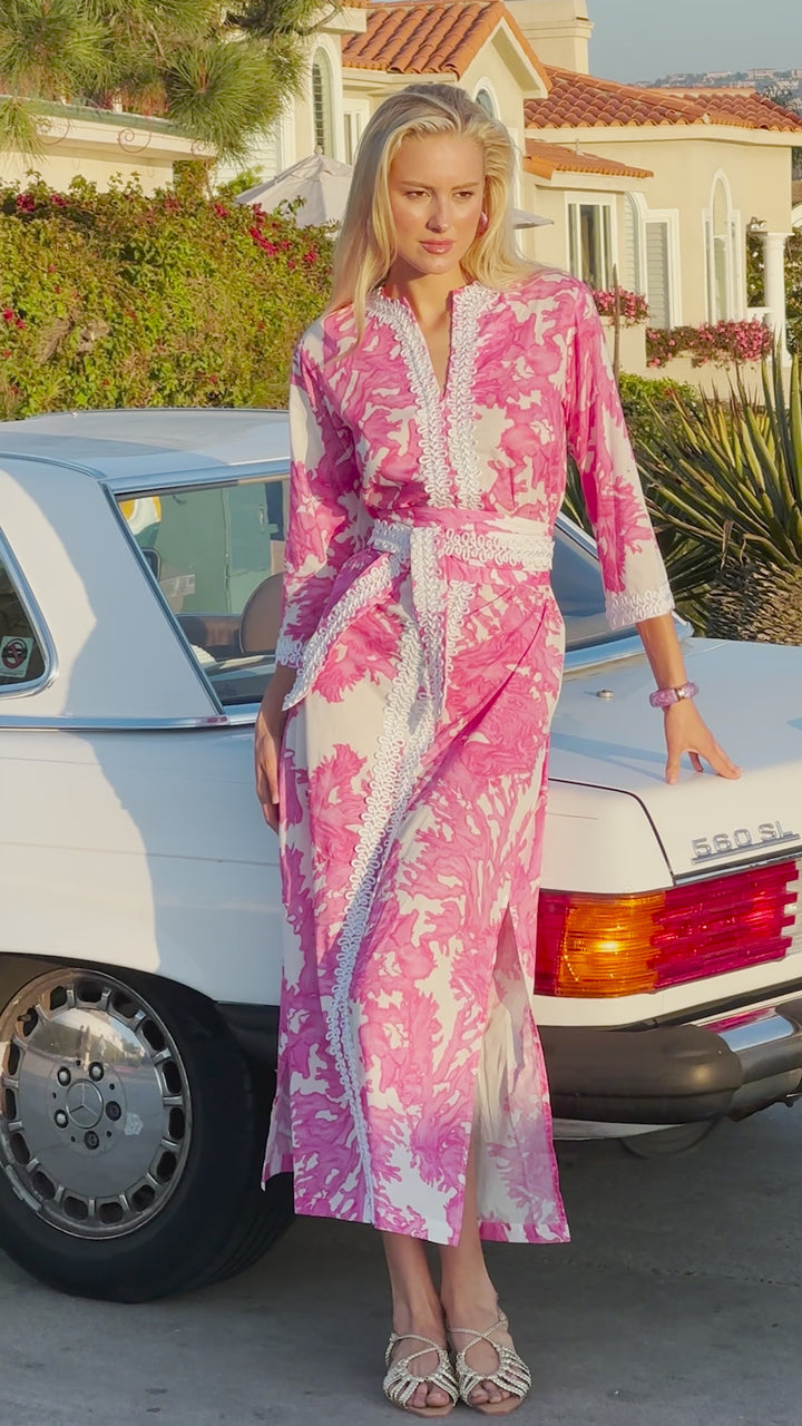 Vide of a woman wearing a pink and white nautical cotton kaftan in front of a vintage car