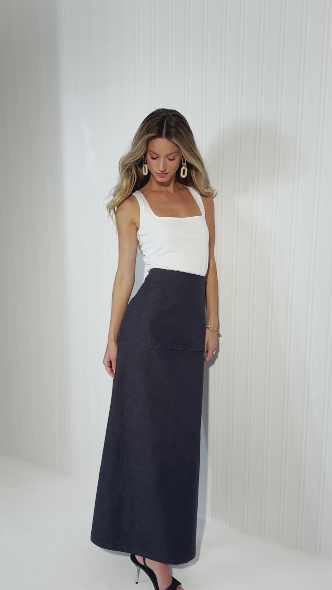 Video of a woman wearing a denim skirt with a white tank top and a matching denim jacket by designer Ala von Auersperg for womens luxury travel clothing