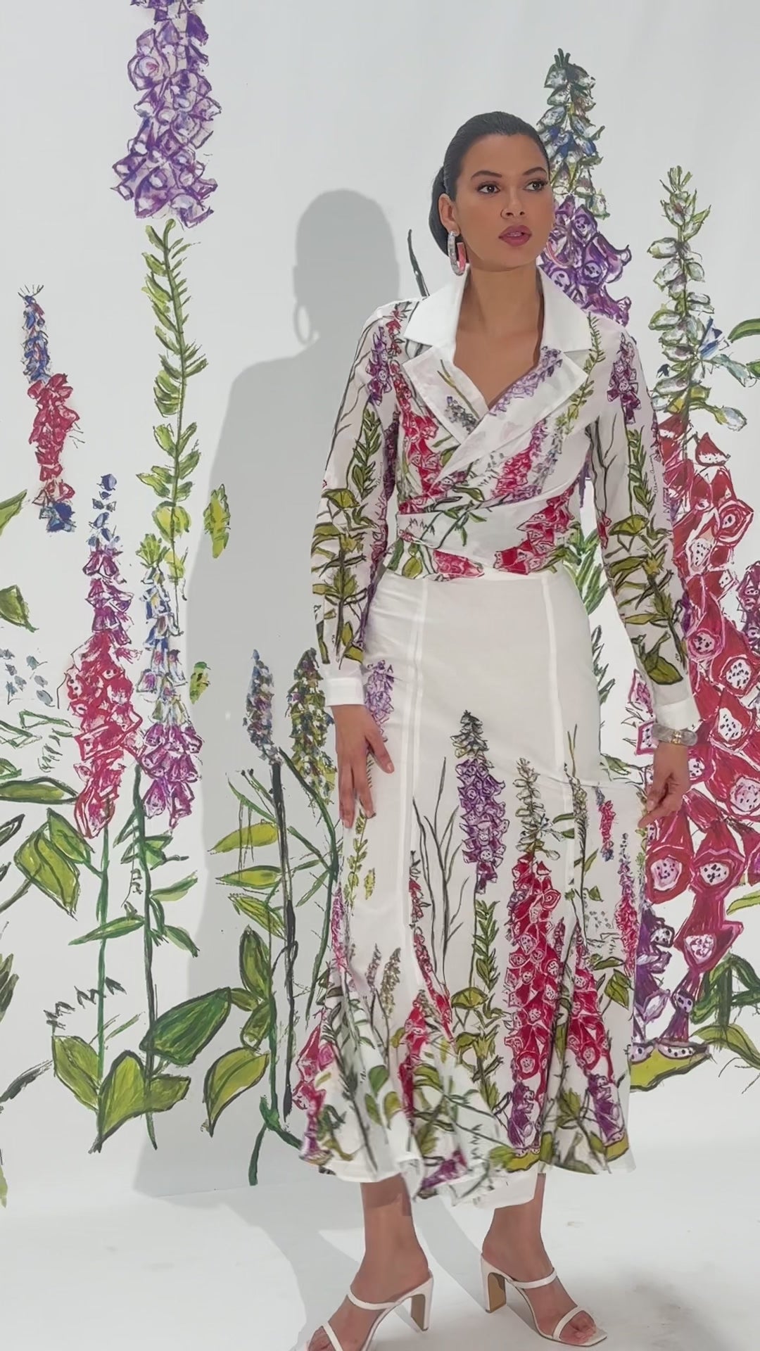 Video of a woman wearing a white cotton skirt with a wrap top in a matching floral print by designer Ala von Auersperg for womens luxury travel clothing