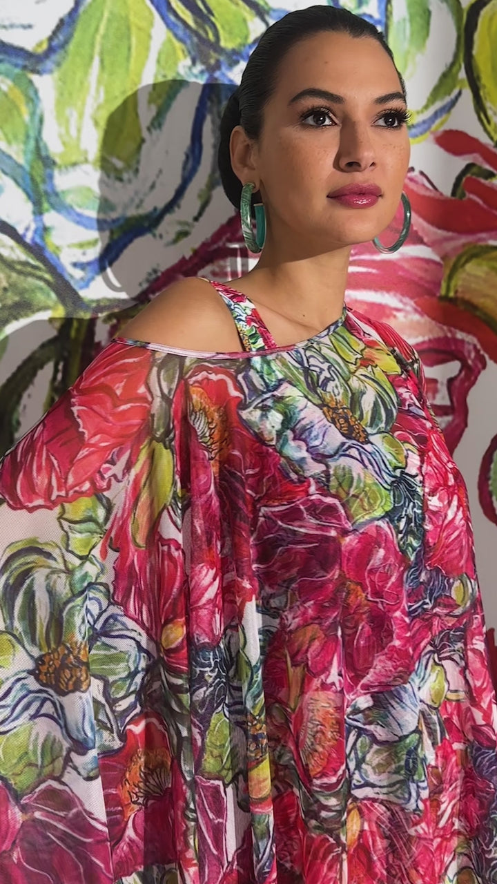 Woman wearing sheer mesh poncho over a matching long dress in a red floral print and over a bathing suit by designer Ala von Auersperg for womens luxury travel clothing