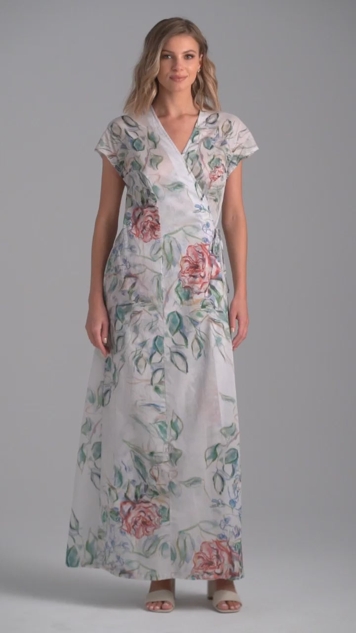 Woman wearing rose printed cotton wrap dress with v neck, side tie, and short sleeves by Ala von Auersperg for summer 2023