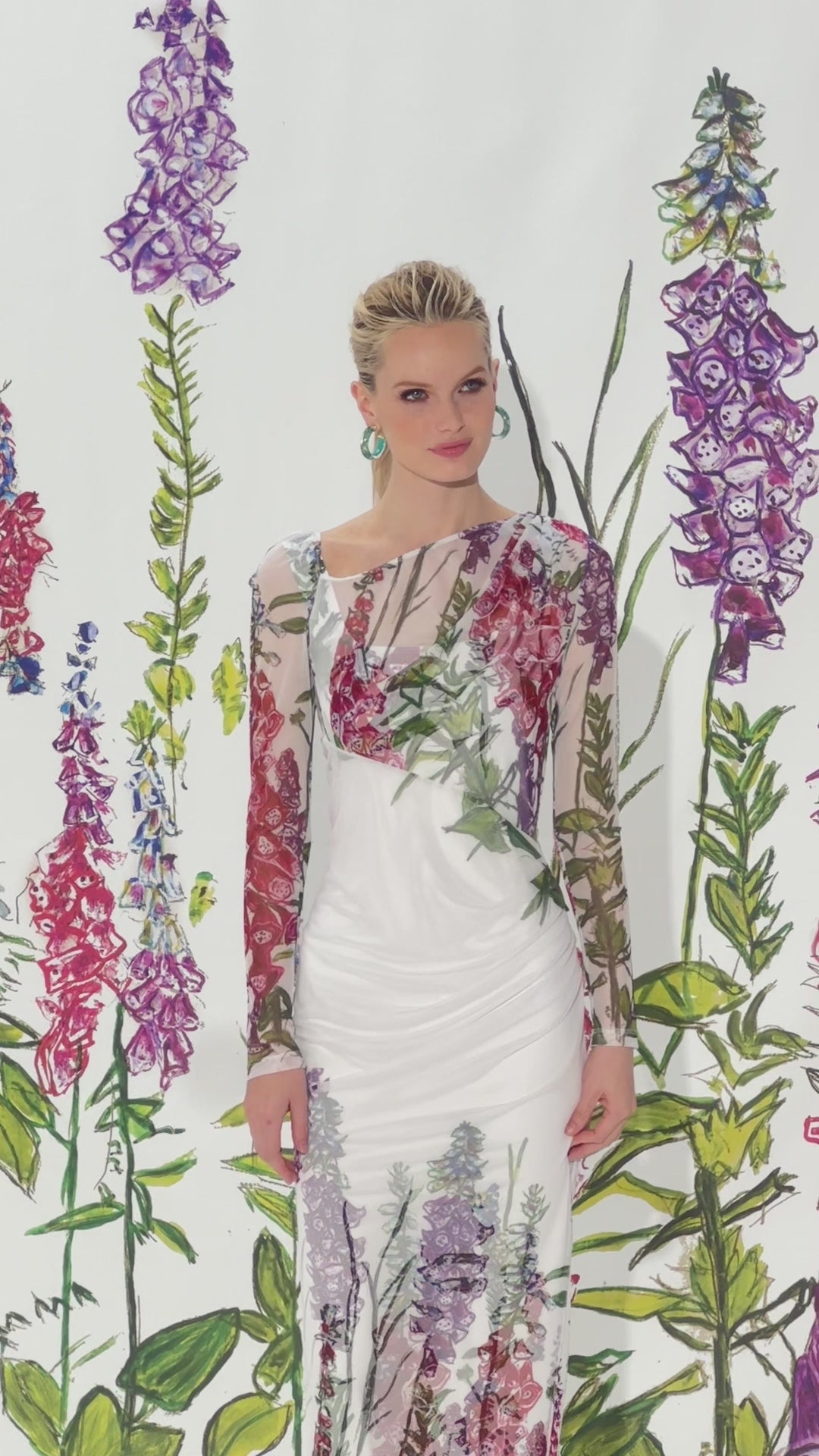 Video of a woman wearing a sheer asymmetrical mesh dress topper over a matching long stretch knit dress in a floral print by designer Ala von Auersperg for womens luxury travel clothing