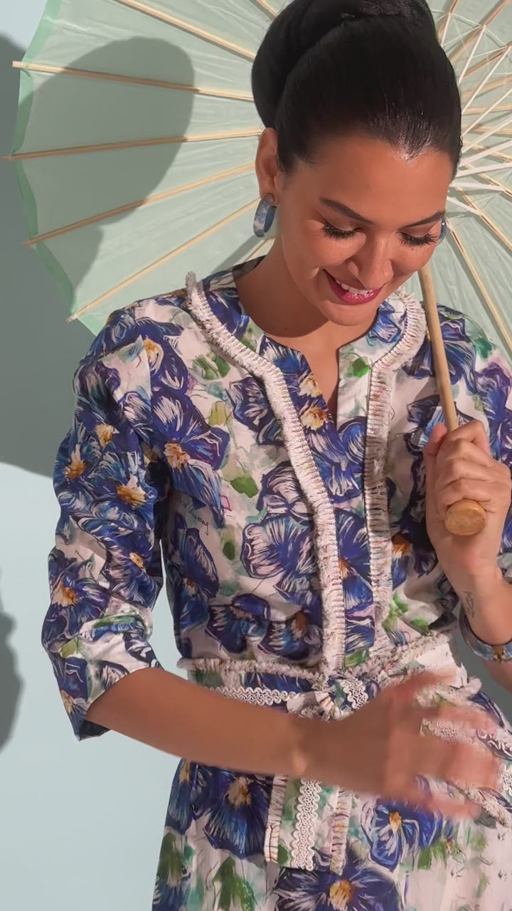 Video of a woman wearing a blue floral cotton tunic with fringe with matching belt and cotton maxi skirt by designer Ala von Auersperg for womens luxury travel clothing