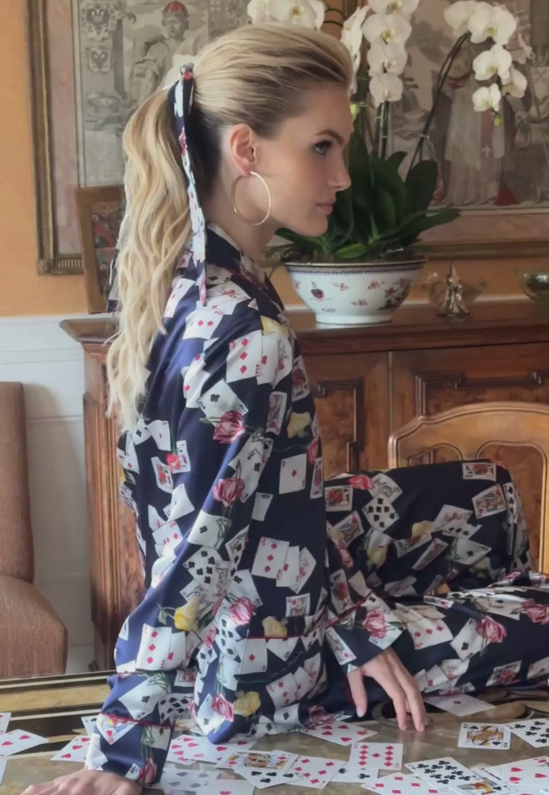 Video of a woman wearing a silk foulard in a card print with matching pajama set