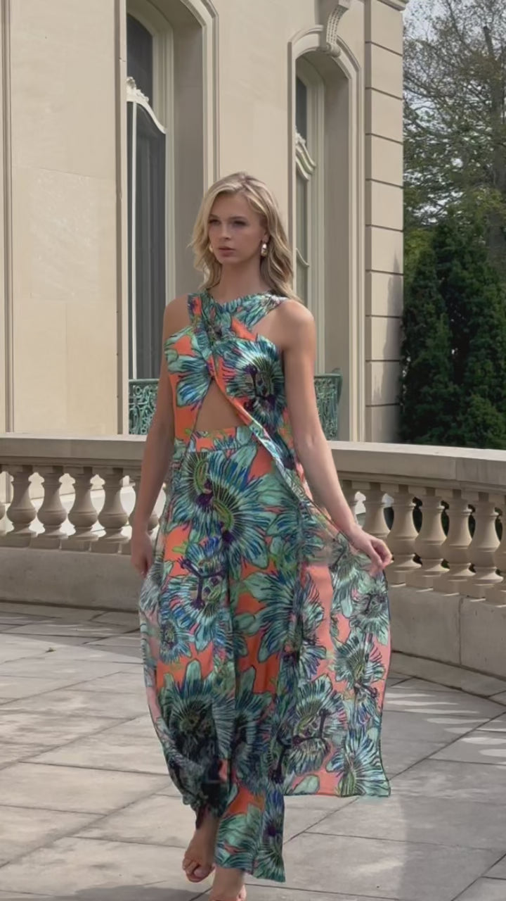 Video of a woman wearing a silk orange and blue green floral top with matching pants outside