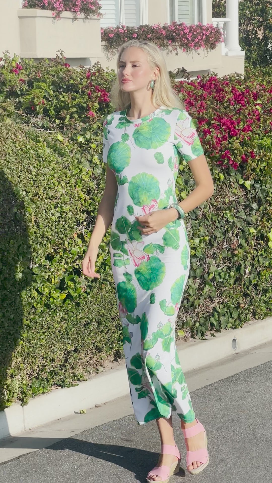 Video of a woman wearing a green floral shirt dress by the water