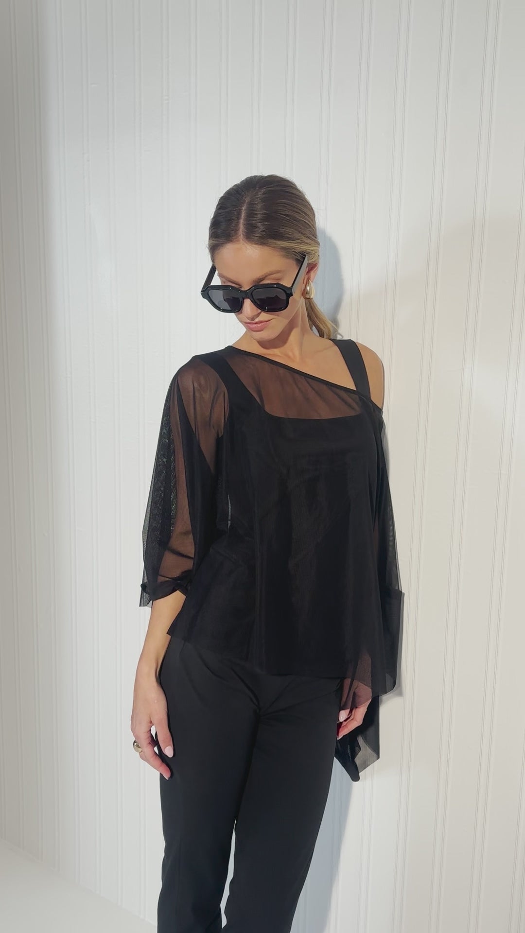 Video of a woman wearing a sheer black mesh top over black tank top and pants by designer Ala von Auersperg for womens luxury travel clothing