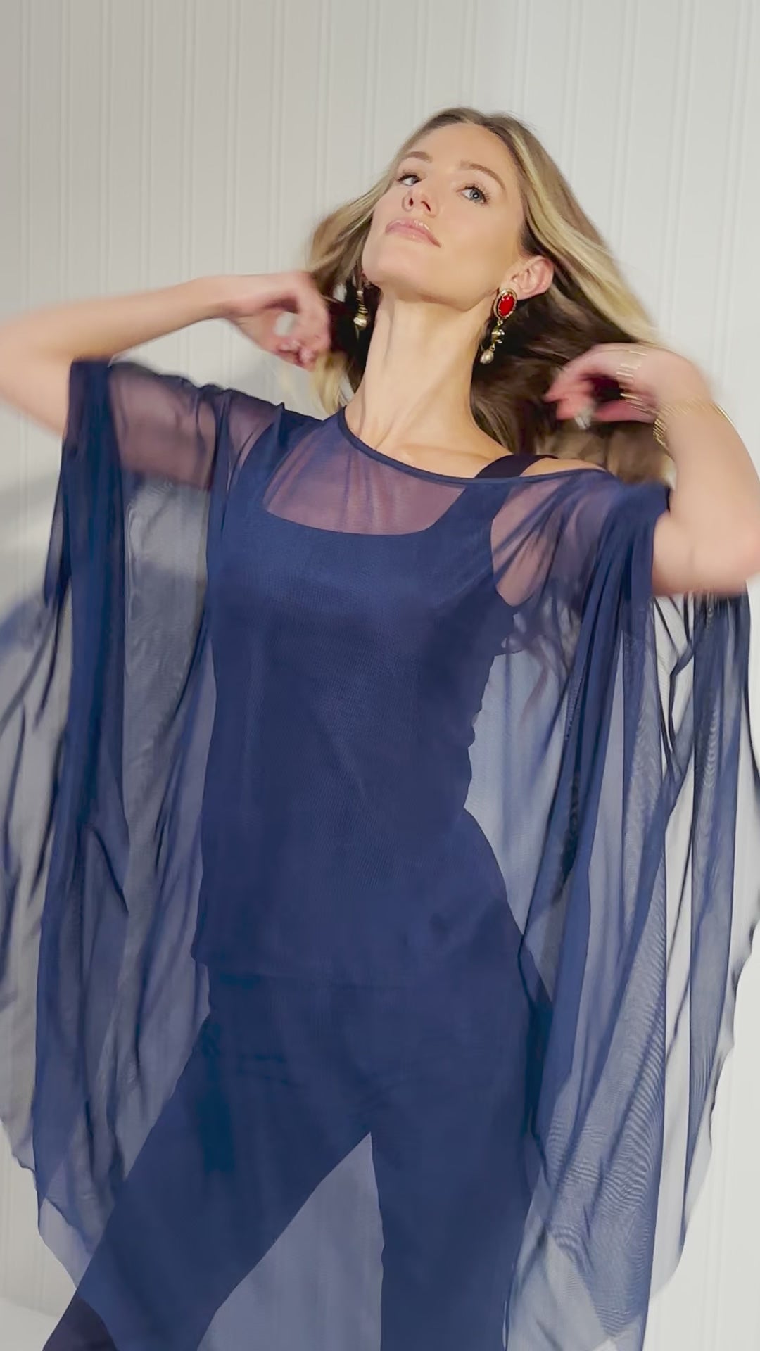 Video of a woman wearing a navy blue sheer mesh poncho over matching navy cotton tank tops and pants by designer Ala von Auersperg for womens luxury travel clothing
