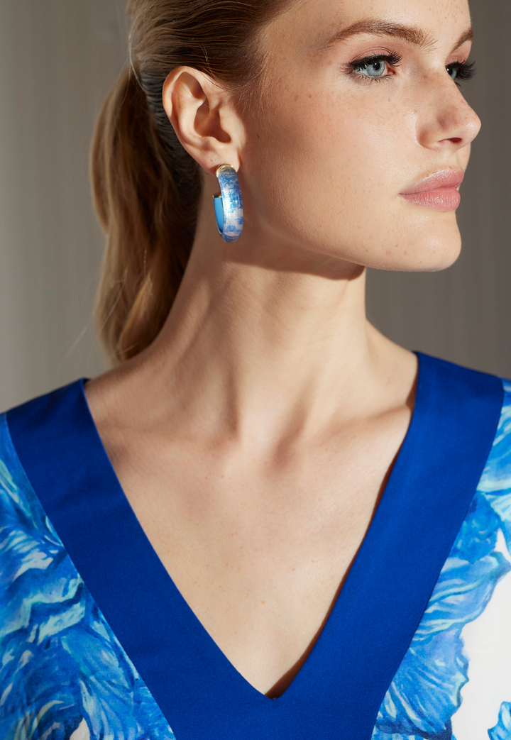 Woman wearing Susan Tahitian Hibiscus silk kaftan with blue trim and coordinating coral jewelry