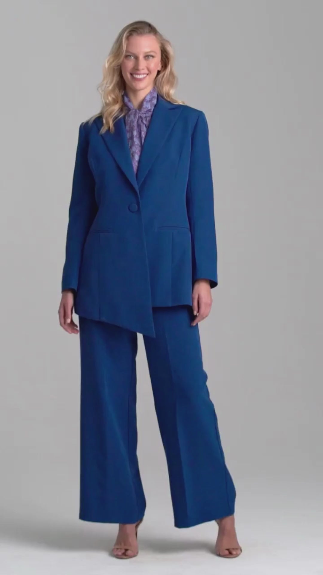 Woman wearing silk lined sapphire blazer with printed cotton bow tie blouse top and stretch blue pants suite by Ala von Auersperg for fall 2022