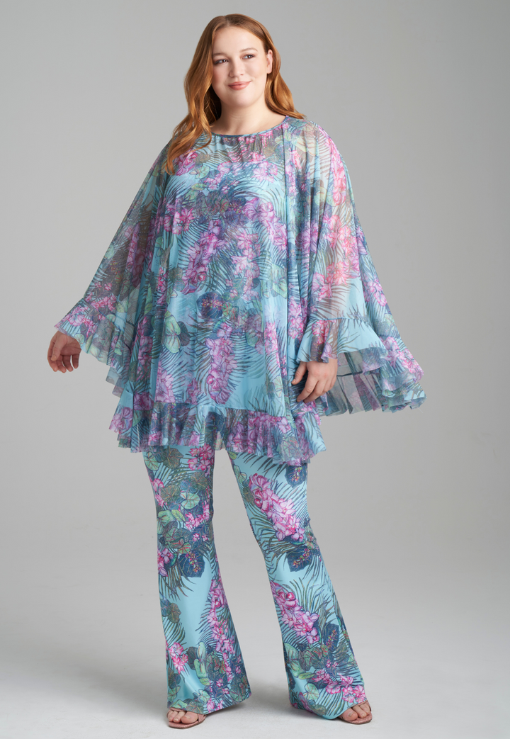 Woman wearing mesh printed orchid and palm poncho over stretch knit tank top and stretch knit pant printed in orchid and palm by Ala von Auersperg for resort 2022
