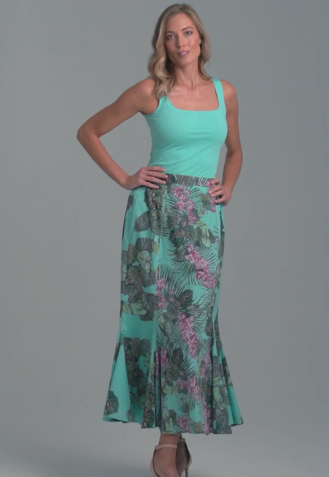 Woman wearing blue stretch knit square neck tank top with cotton grape leaf and orchid printed green cotton peasant skirt by Ala von Auersperg for resort 2022