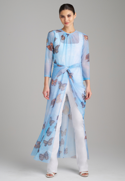 Woman wearing mesh blue butterfly printed asymmetrical topper over italian white stretch cotton tank top and pants by Ala von Auersperg for spring 2023