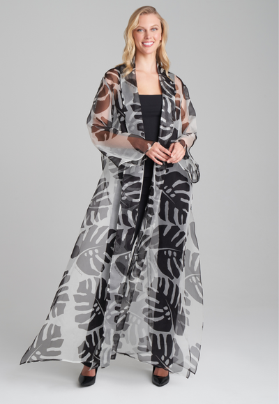 Woman wearing silk black and white palm leaf printed printed organza long jacket duster over italian stretch cotton square neck tank top and pant in black by Ala von Auersperg for holiday 2022