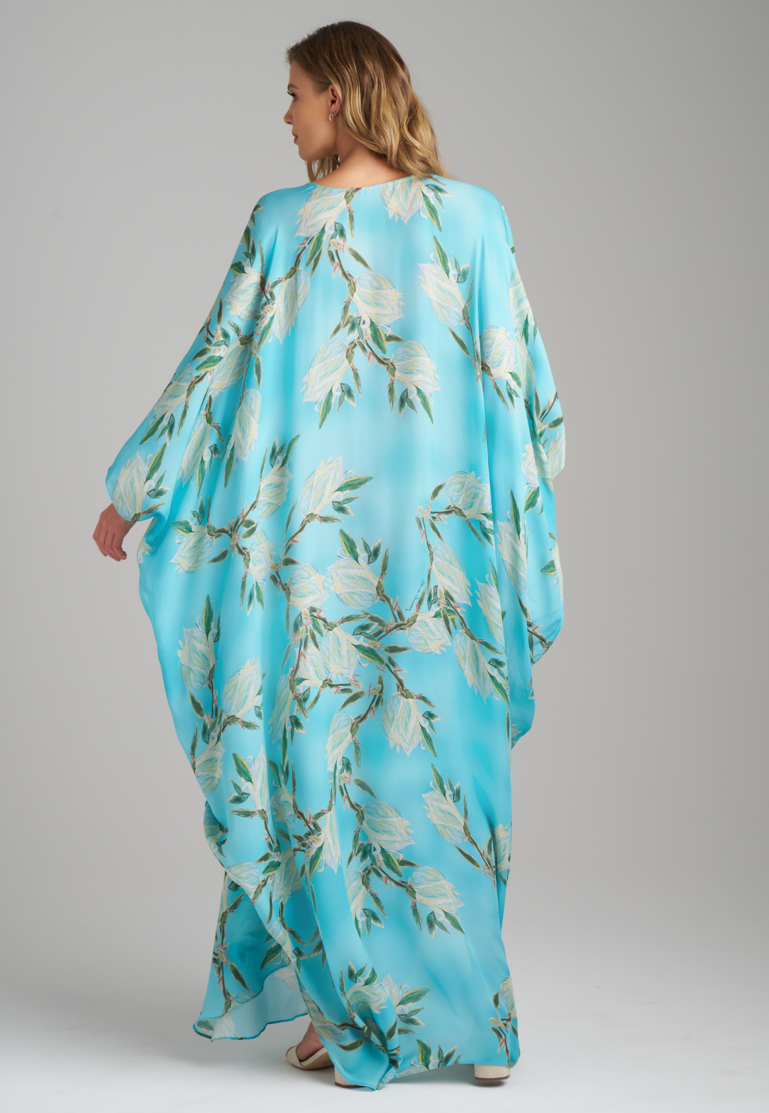 Woman wearing blue silk yucca printed long kaftan with v neck by Ala von Auersperg for spring 2023