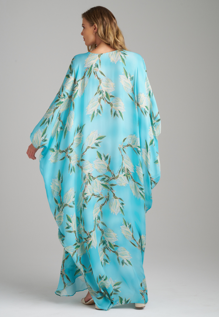 Woman wearing blue silk yucca printed long kaftan with v neck by Ala von Auersperg for spring 2023
