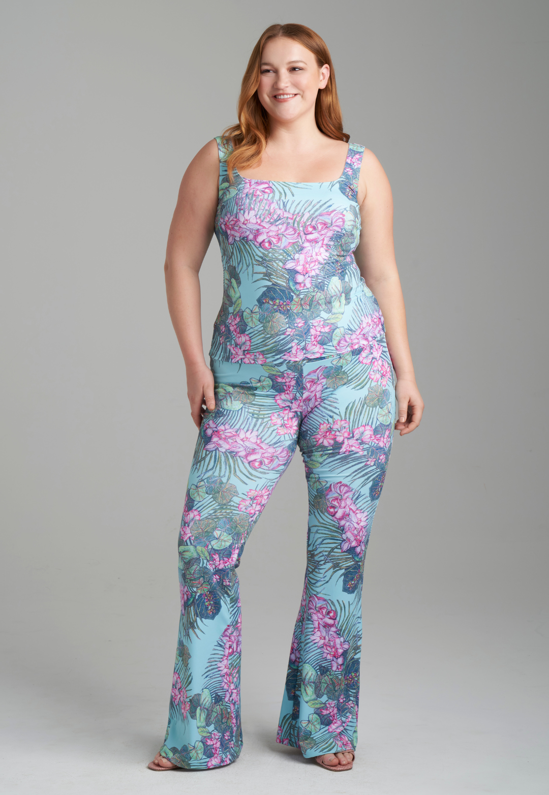 Woman wearing orchid and palm printed square neck stretch knit tank top and orchid and palm printed skinny leg pants by Ala von Auersperg for resort 2022
