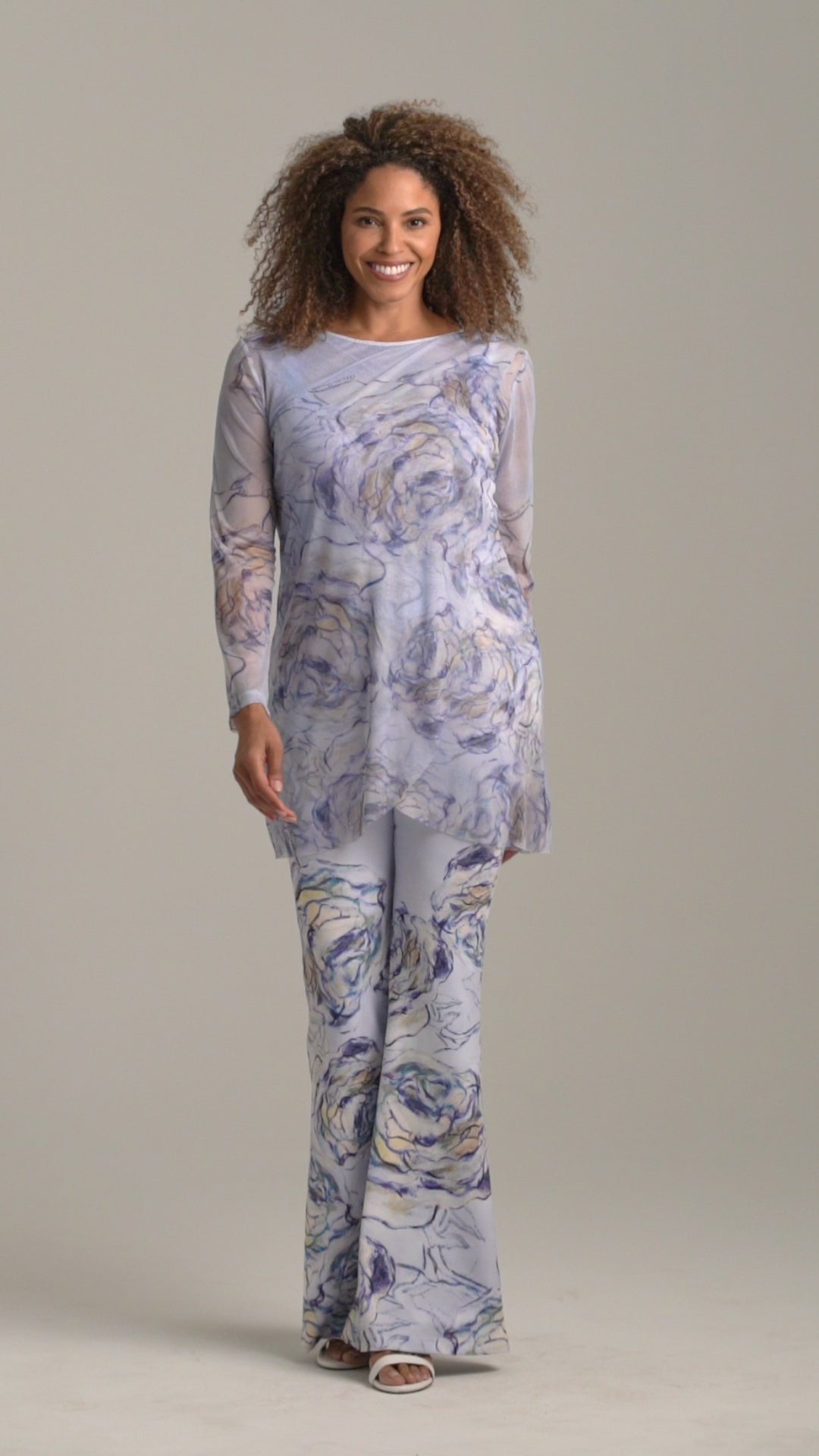 Woman wearing blue rose printed mesh tunic over blue rose printed stretch knit tank top and pants by Ala von Auersperg for spring summer 2022