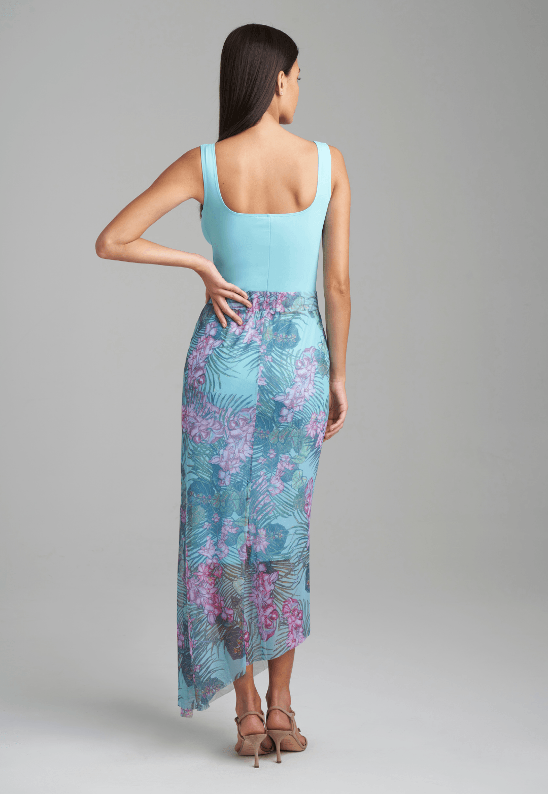 Woman wearing stretch knit tank top in blue with mesh printed orchid and palm green skirt by Ala von Auersperg for resort 2022