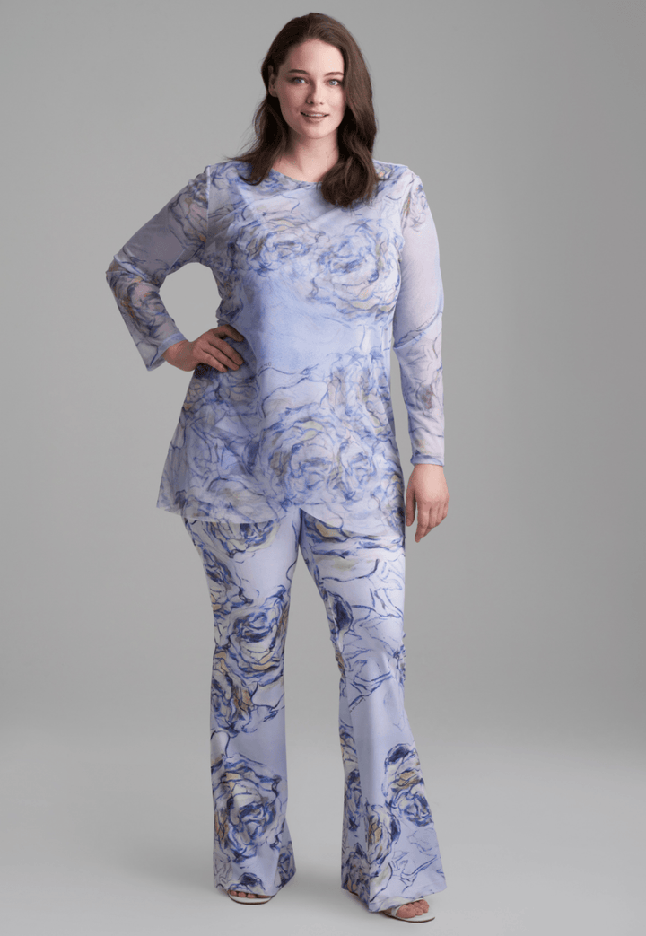 Woman wearing blue rose printed mesh tunic over blue rose printed stretch knit tank top and pants by Ala von Auersperg for spring summer 2022