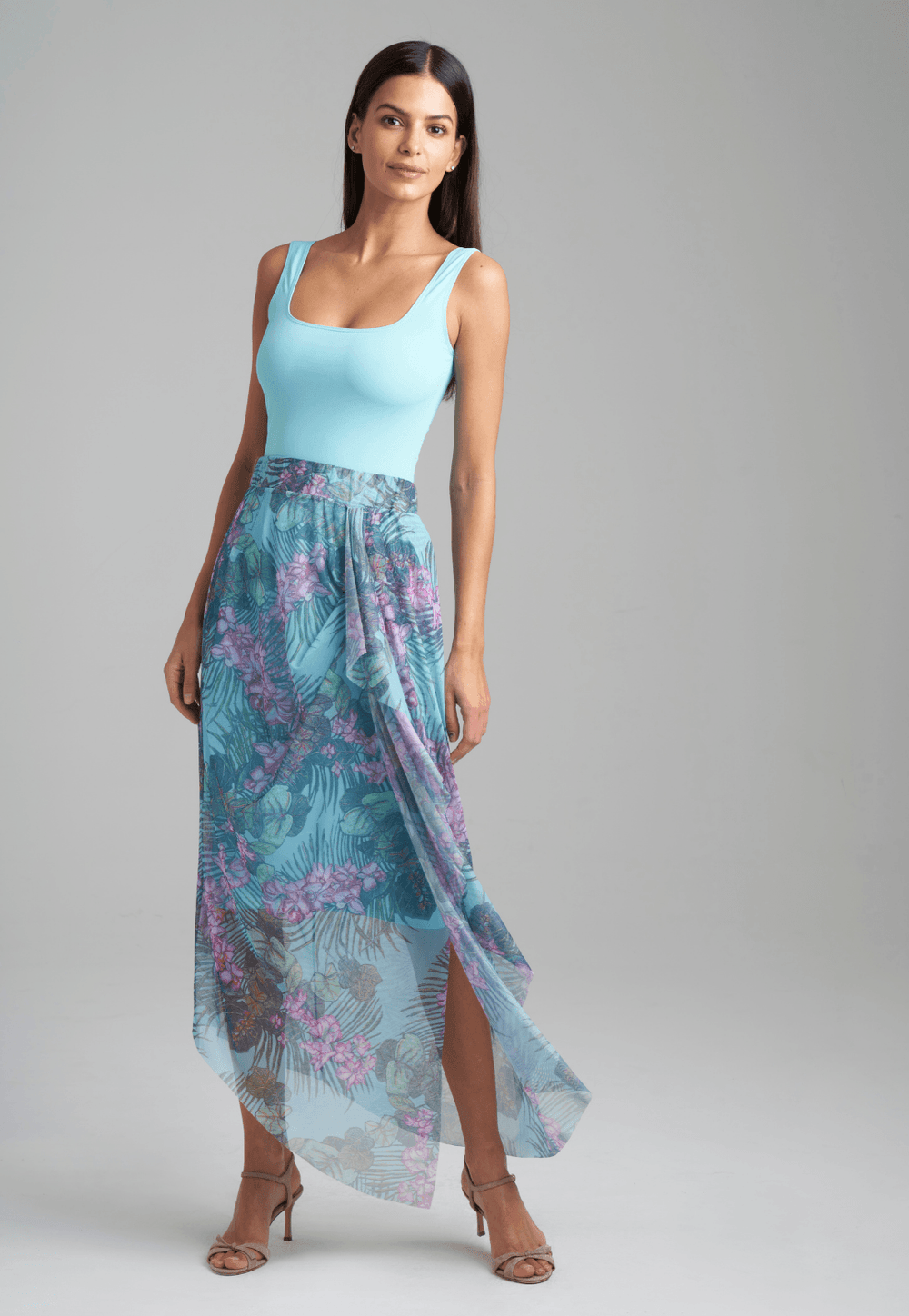 Woman wearing stretch knit tank top in blue with mesh printed orchid and palm green skirt by Ala von Auersperg for resort 2022
