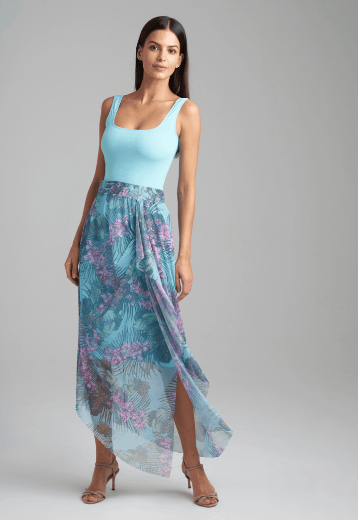 Woman wearing stretch knit tank top in blue with mesh printed orchid and palm green skirt by Ala von Auersperg for resort 2022
