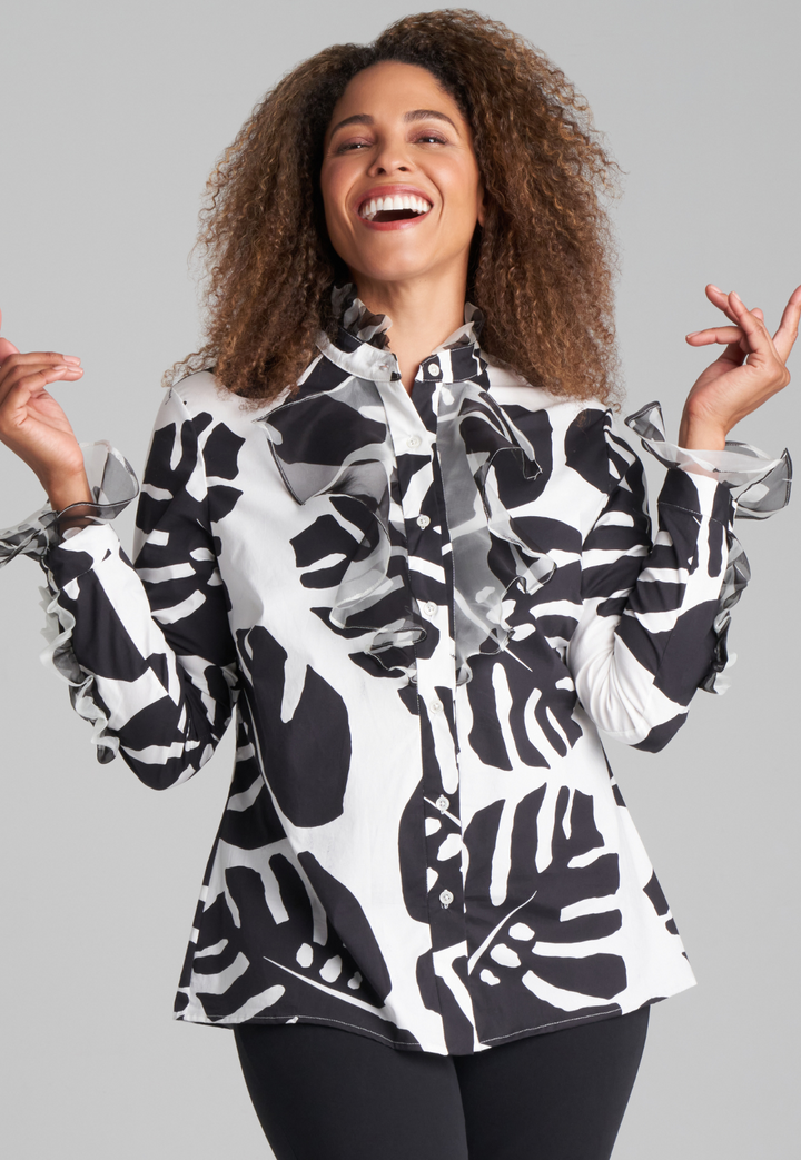 Woman wearing cotton turtleneck black and white palm leaf printed blouse with ruffle sleeve and collar details with italian stretch cotton pant in black by Ala von Auersperg for holiday 2022