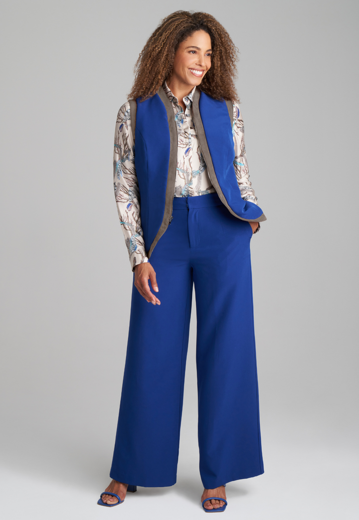 Woman wearing silk lined blue blazer over feather printed silk shirt and stretch knit blue pants by Ala von Auersperg for fall 2022